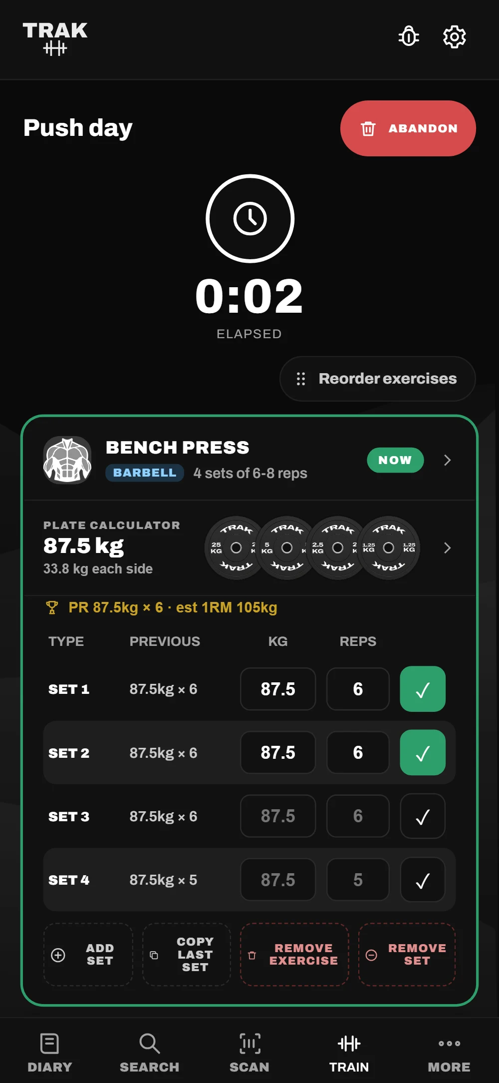 A live TRAK workout: bench press with two sets ticked off, the plate calculator loading 87.5 kg, and a personal record line.